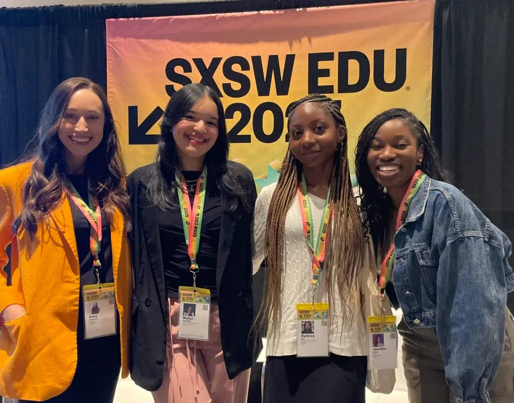Students smiling in front of a SXSW banner.